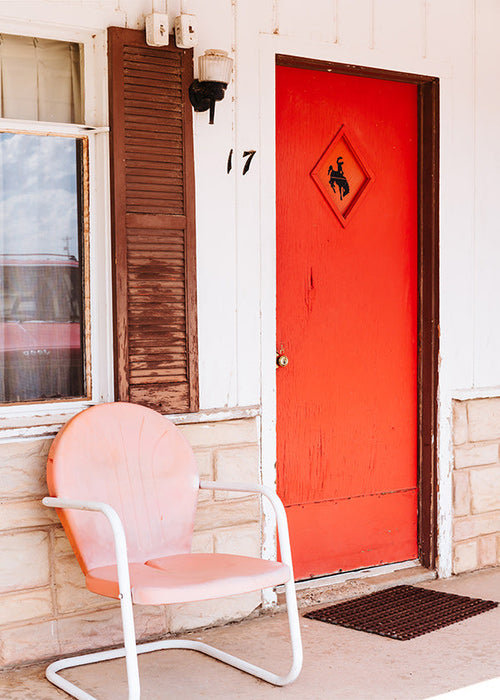 Fotografia de motel com porta vermelha e cadeira retro